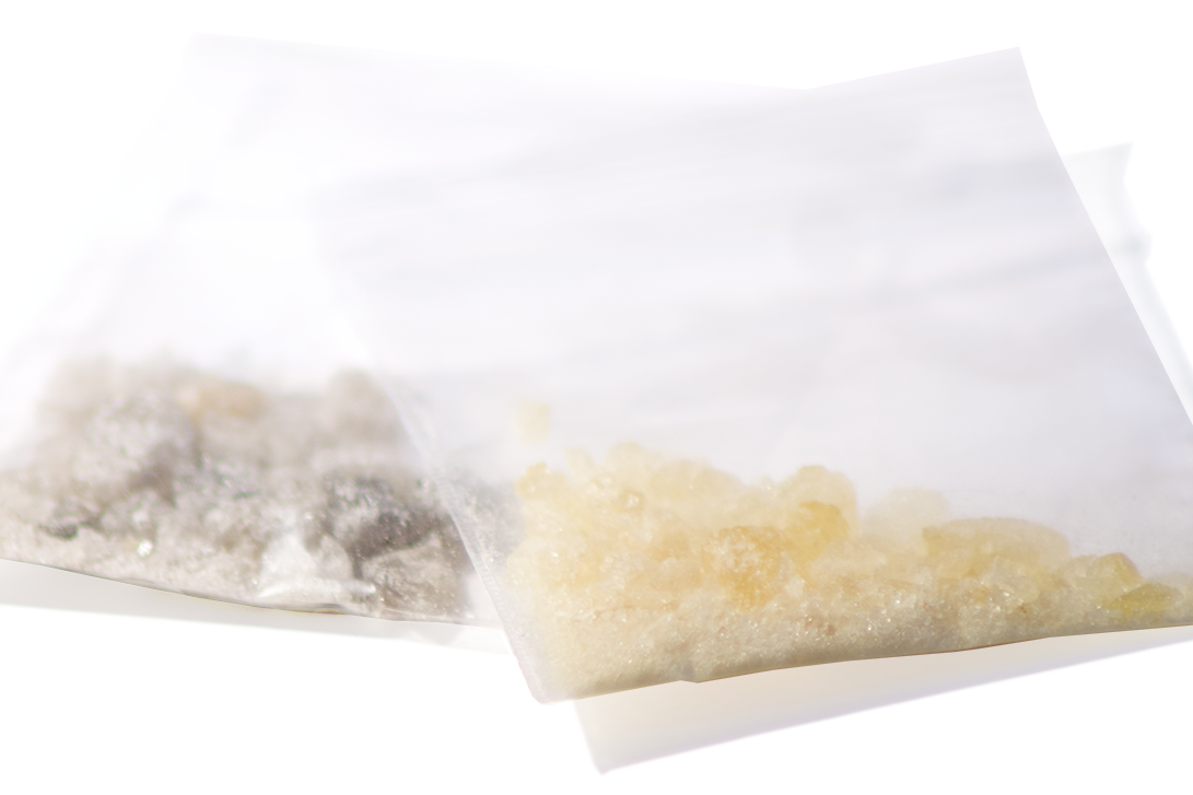 Dos bolsitas transparentes con cristales de MDMA sobre fondo blanco