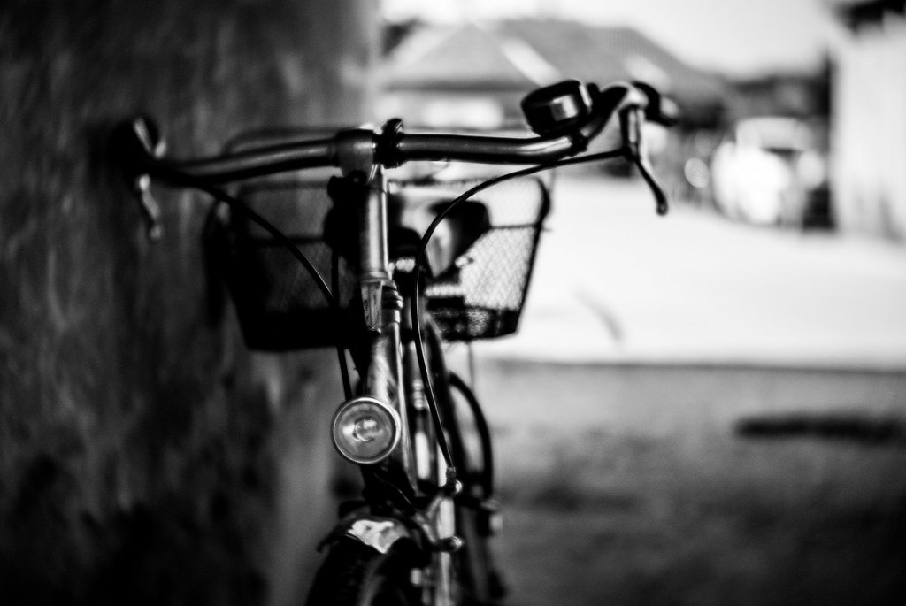 Manillar y cesta de una bicicleta antigua fotografiados en blanco y negro con fondo desenfocado