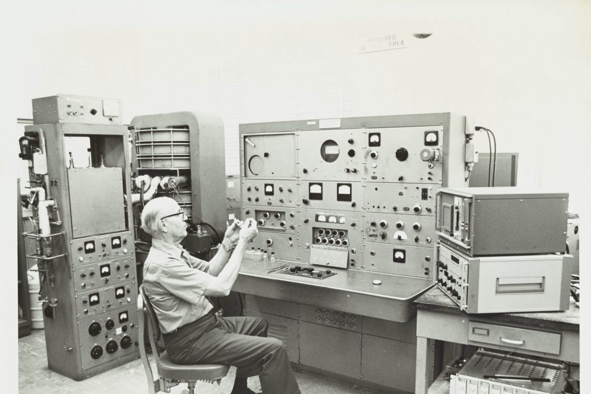 Fotografía histórica en blanco y negro de un químico operando un espectrómetro de masas en un laboratorio de investigación