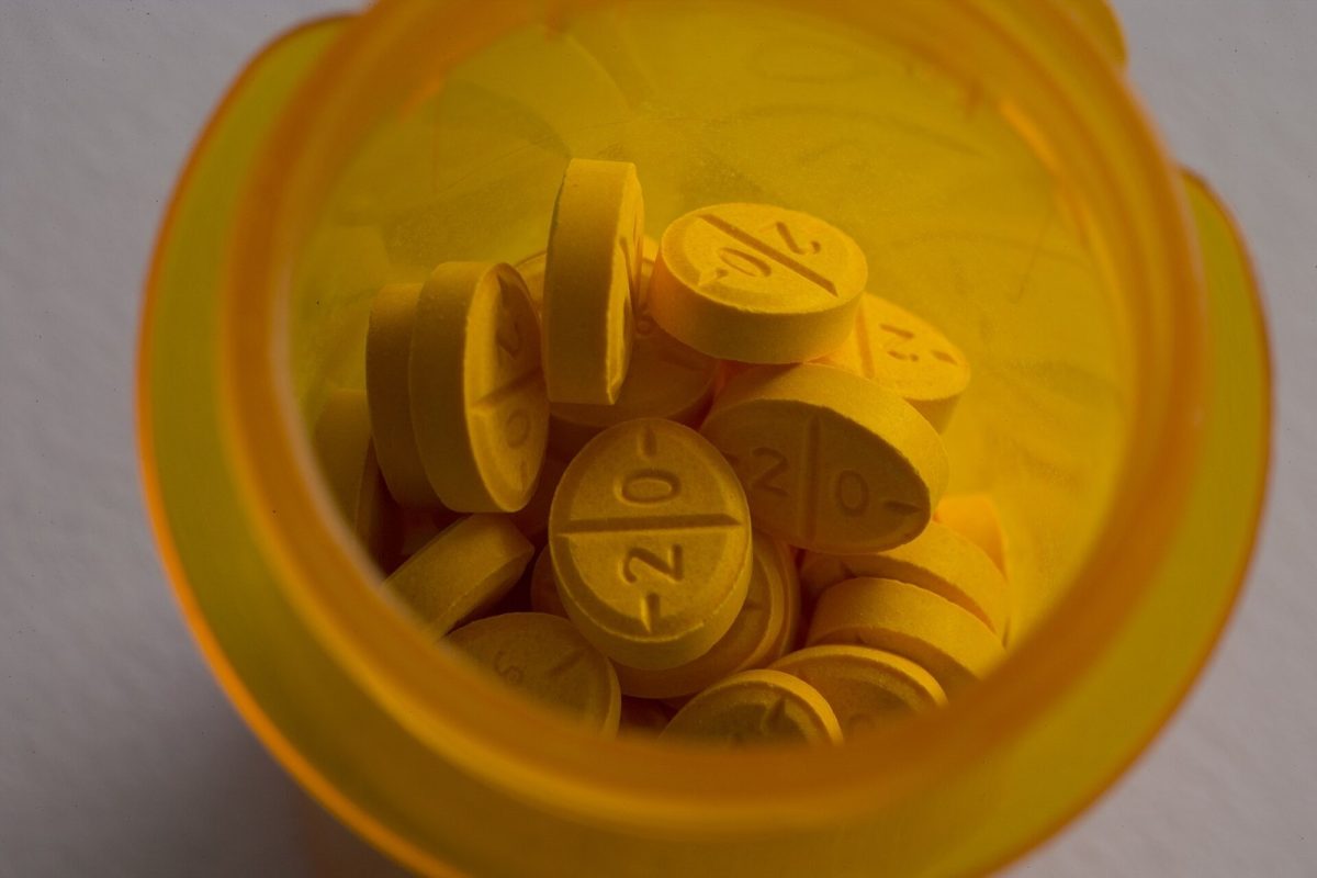 Primer plano de pastillas amarillas grabadas con el número 20 dentro de un bote de medicamentos