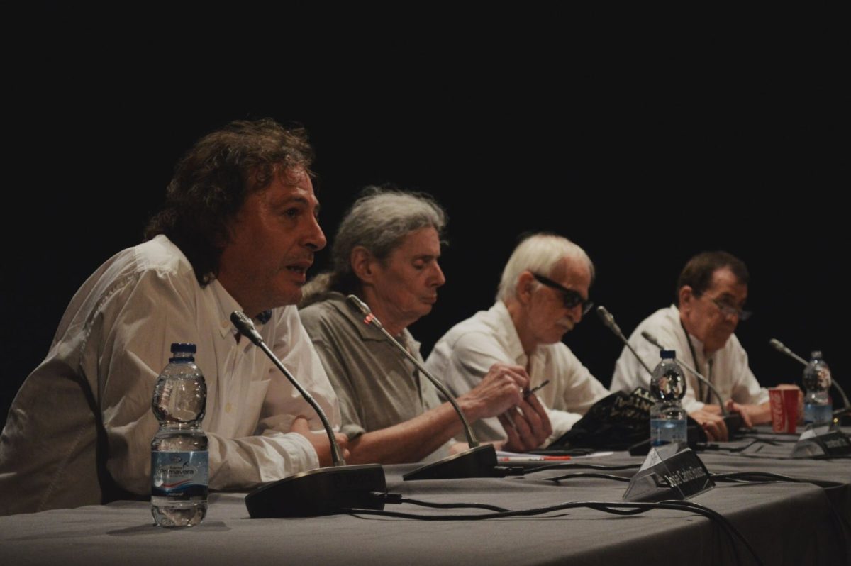 Antonio Escohotado junto a otros ponentes sentados a una mesa con micrófonos durante una conferencia sobre ayahuasca en Ibiza