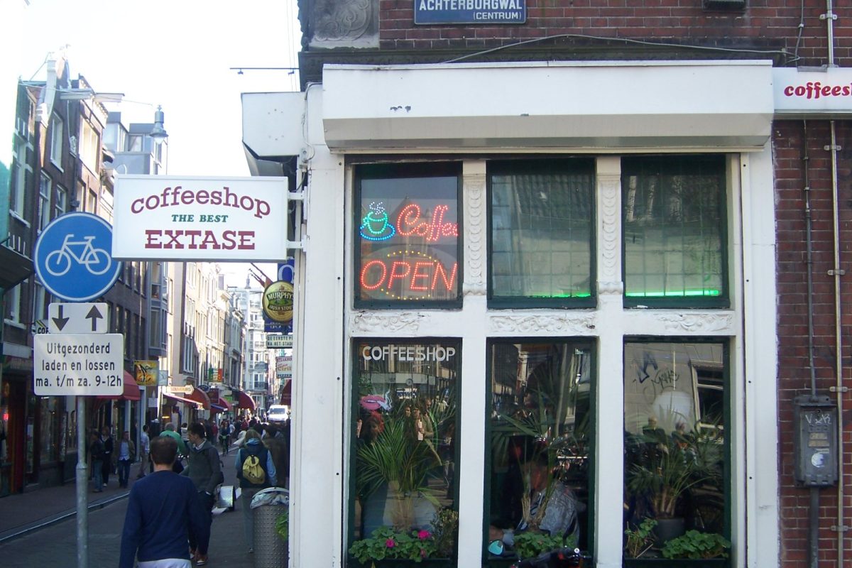 Fachada de un coffee shop en una calle del centro de Ámsterdam, con transeúntes y bicicletas