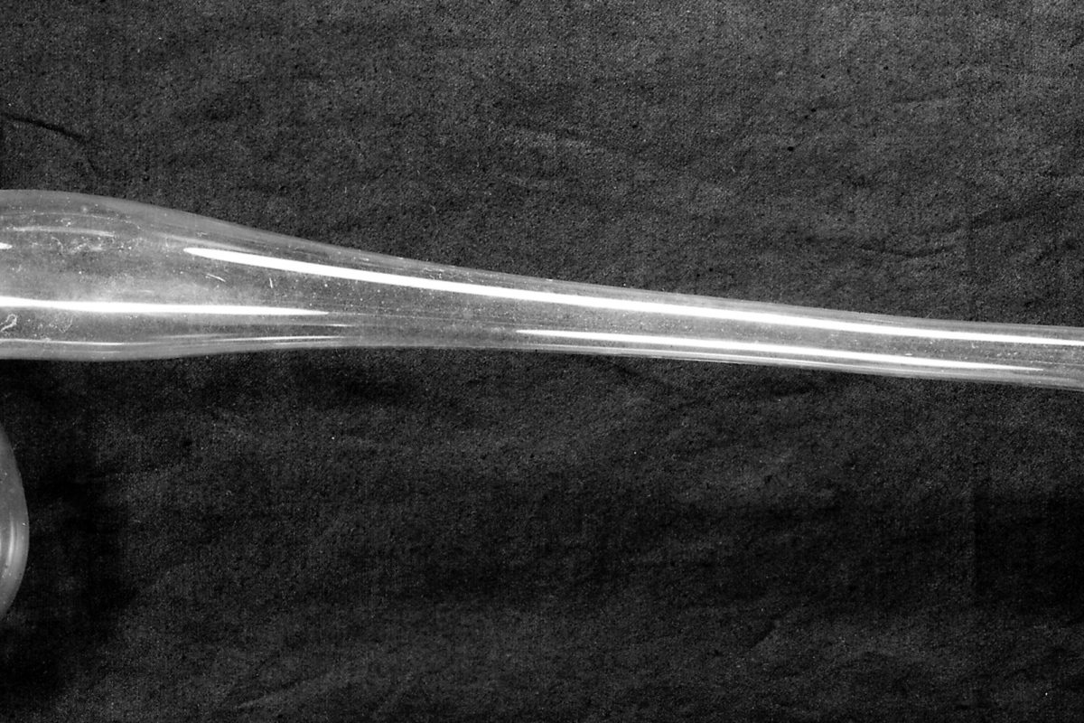 Fotografía en blanco y negro de una retorta de vidrio de laboratorio del siglo XIX, con cuello alargado y tapón