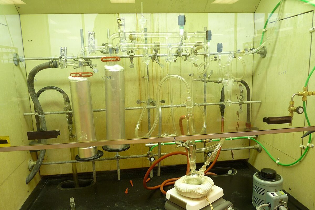 Vitrina de laboratorio de química con una rampa de vacío, matraces y tubos de vidrio, mangueras y un montaje de destilación sobre una placa calefactora