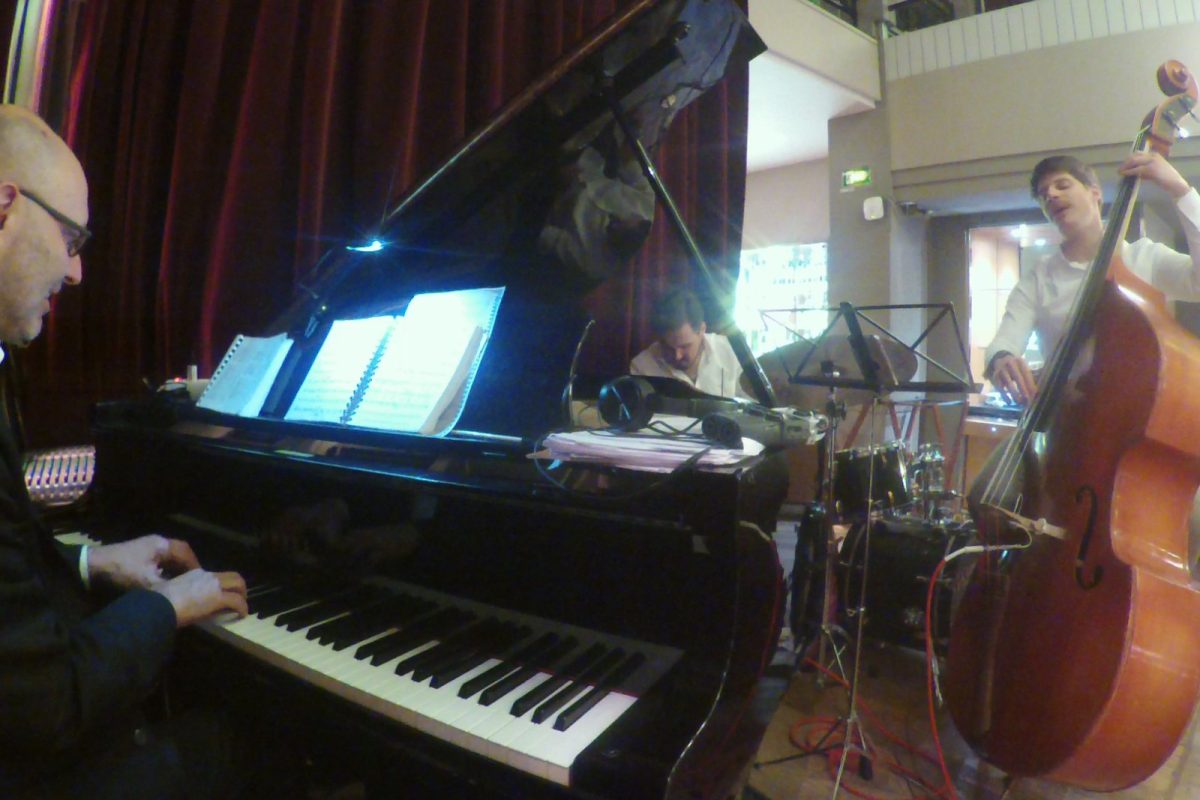 Músicos de jazz tocando piano, contrabajo y batería en un concierto íntimo