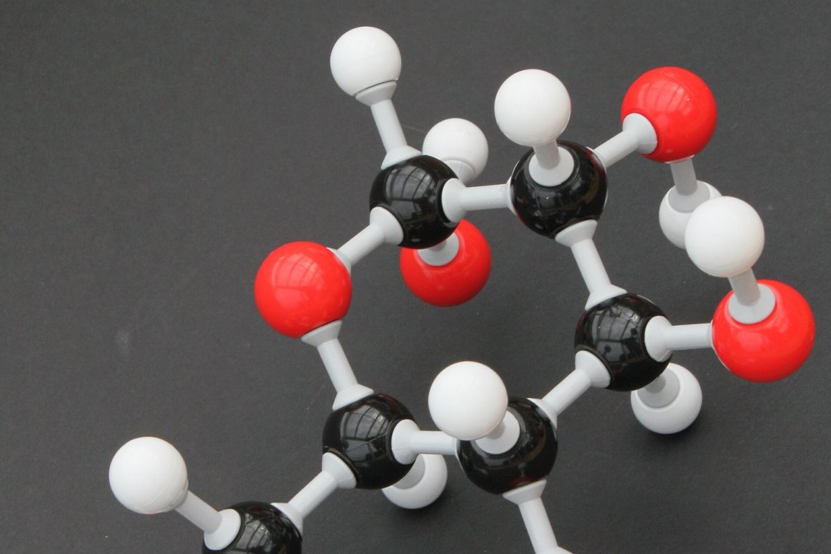 Modelo molecular tridimensional de una molécula orgánica construido con bolas negras, blancas y rojas sobre fondo oscuro
