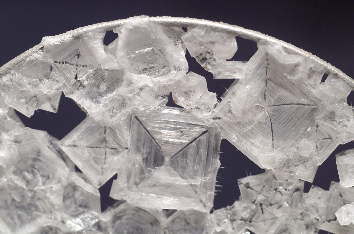 Primer plano macro de cristales cúbicos de sal común (cloruro de sodio) sobre fondo oscuro