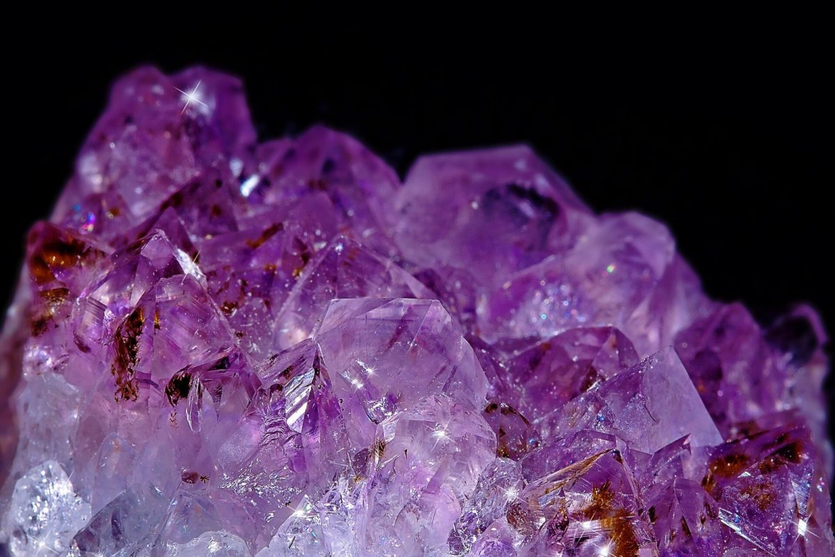 Primer plano de un cúmulo de cristales de amatista violeta con reflejos brillantes sobre fondo oscuro