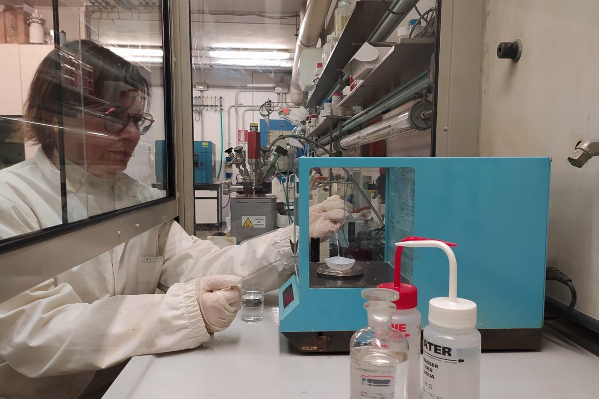 Química trabajando con frascos de reactivos dentro de una vitrina de extracción de gases en un laboratorio