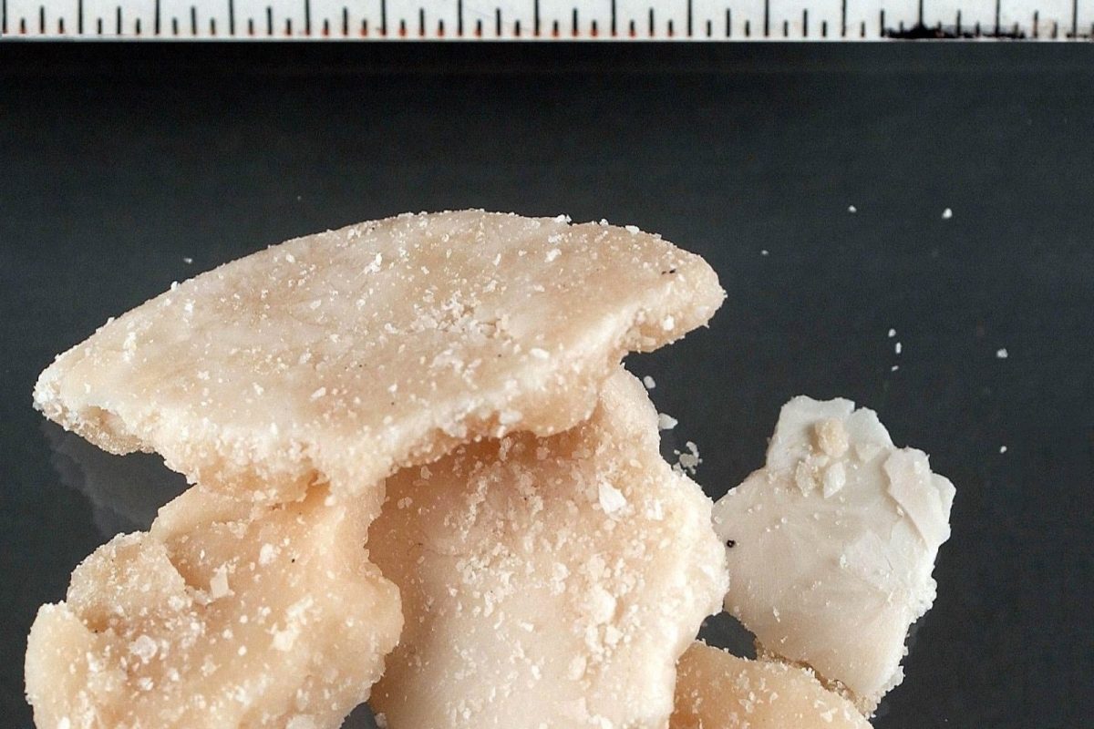 Fotografía forense de varios fragmentos irregulares de crack (cocaína base) de color beige claro, junto a una regla de medición.