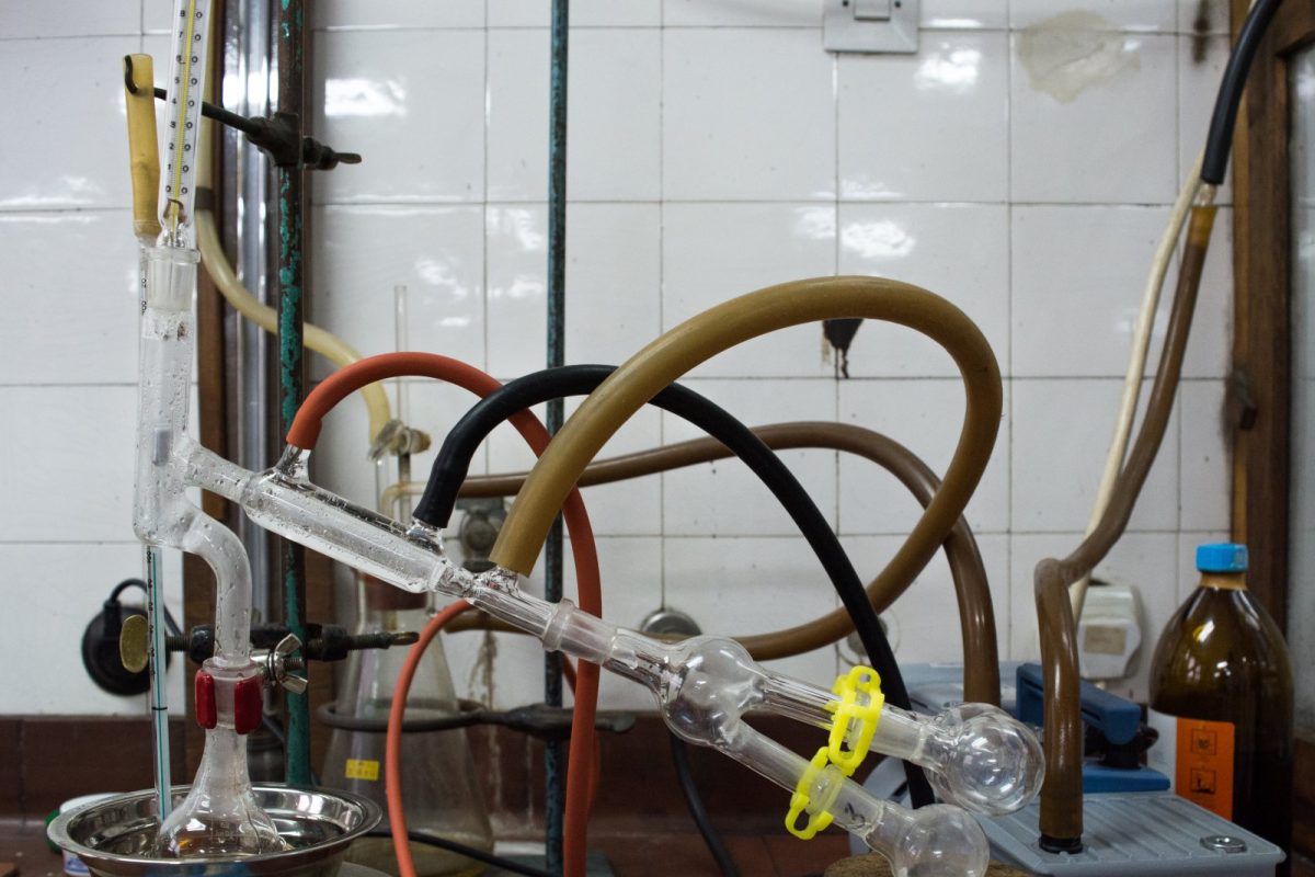 Montaje de destilación al vacío con matraces y refrigerante de vidrio conectados mediante tubos a una bomba de vacío, sobre una mesa de laboratorio