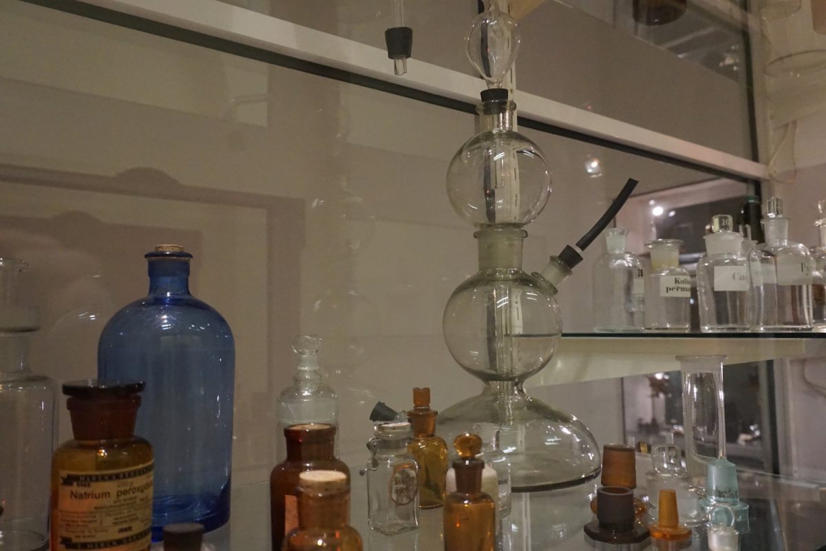 Vitrina de laboratorio antigua con matraces, alambiques de vidrio y frascos de reactivos etiquetados