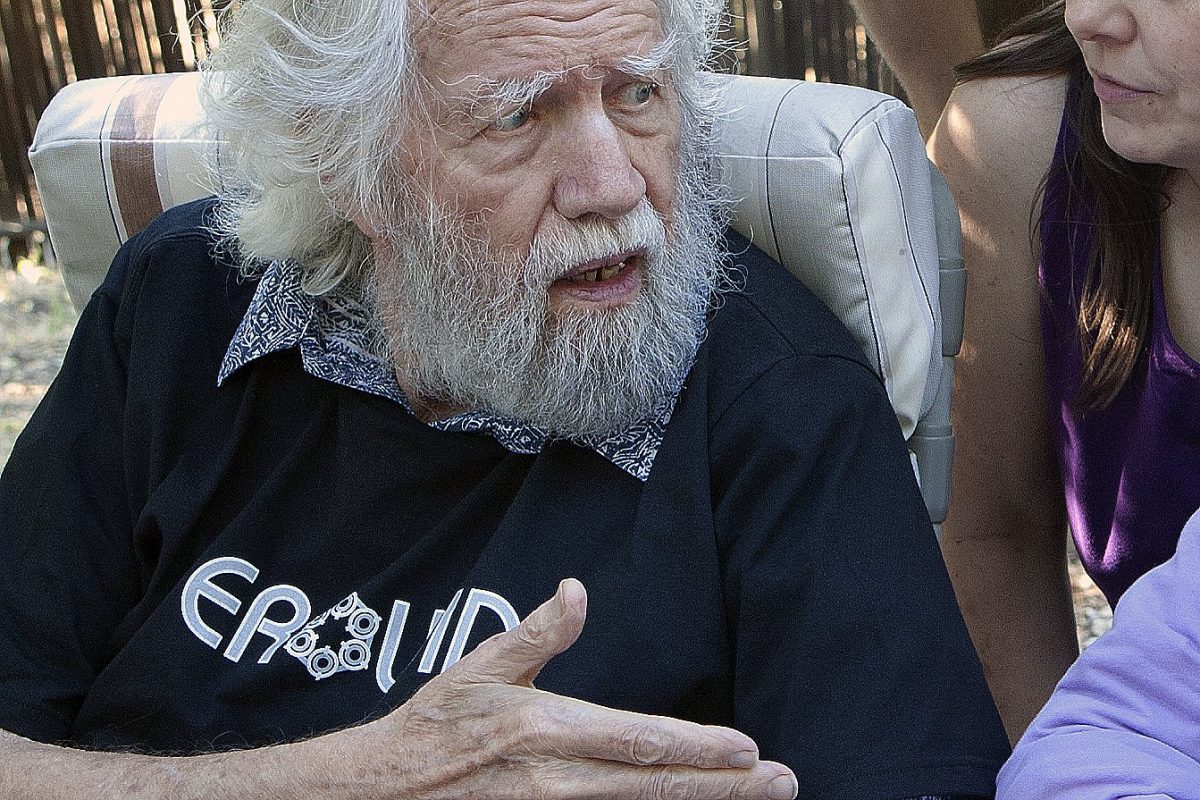 Primer plano de Alexander Shulgin, con barba y cabello blancos, gesticulando mientras habla al aire libre