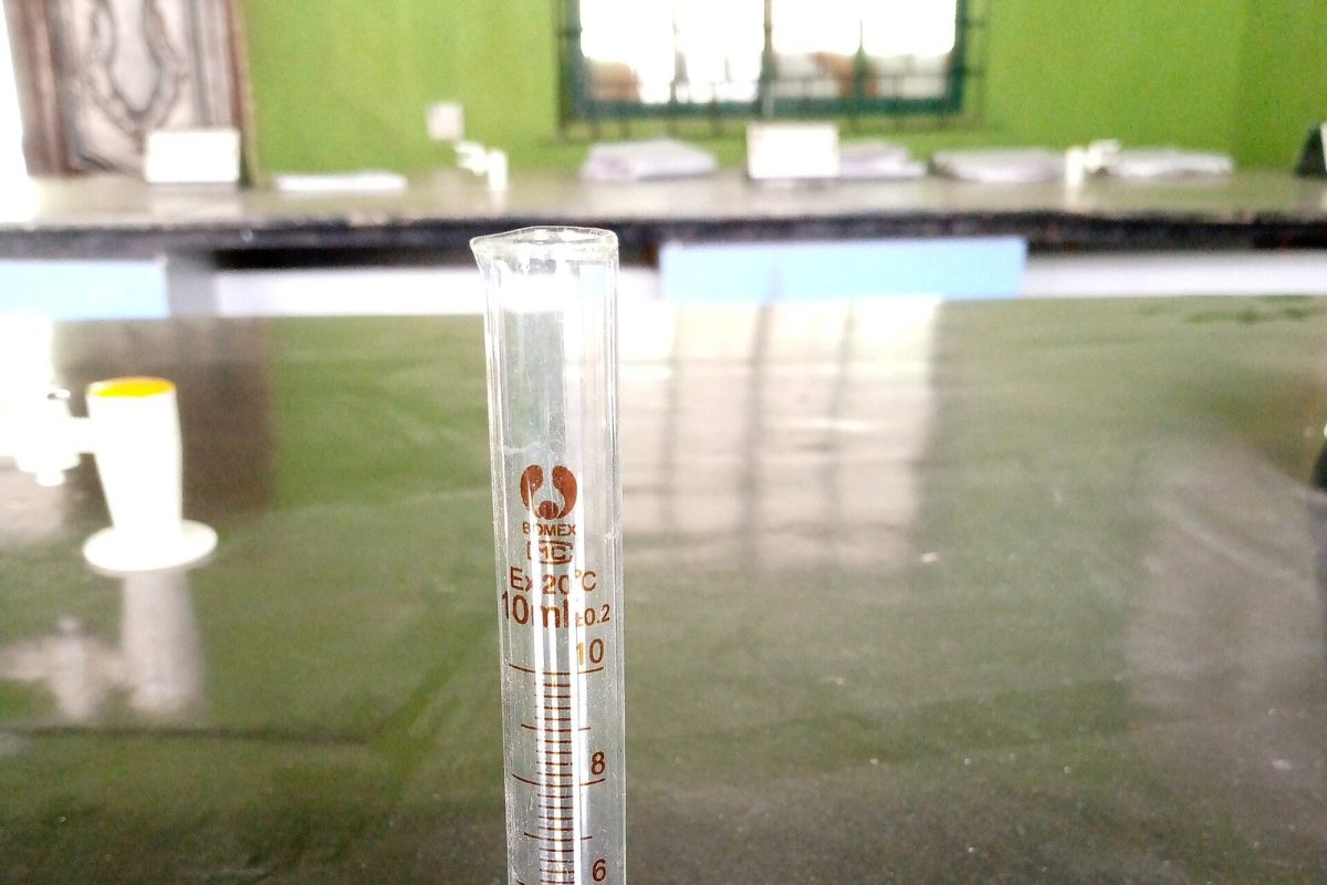 Probeta de vidrio graduada de pie sobre una mesa de laboratorio