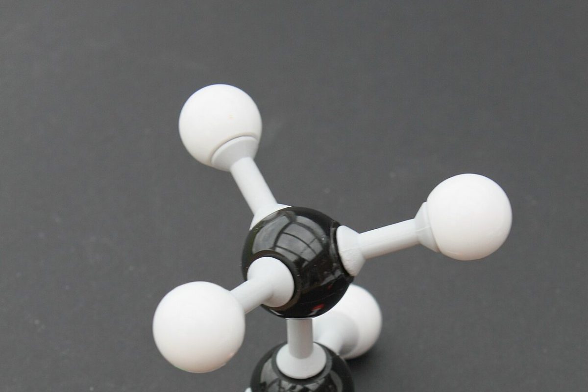 Modelo molecular de bolas y varillas con esferas verde y naranja que representan cloro y bromo