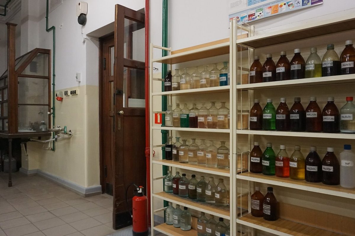 Estantería de laboratorio repleta de frascos de vidrio con reactivos químicos de distintos colores