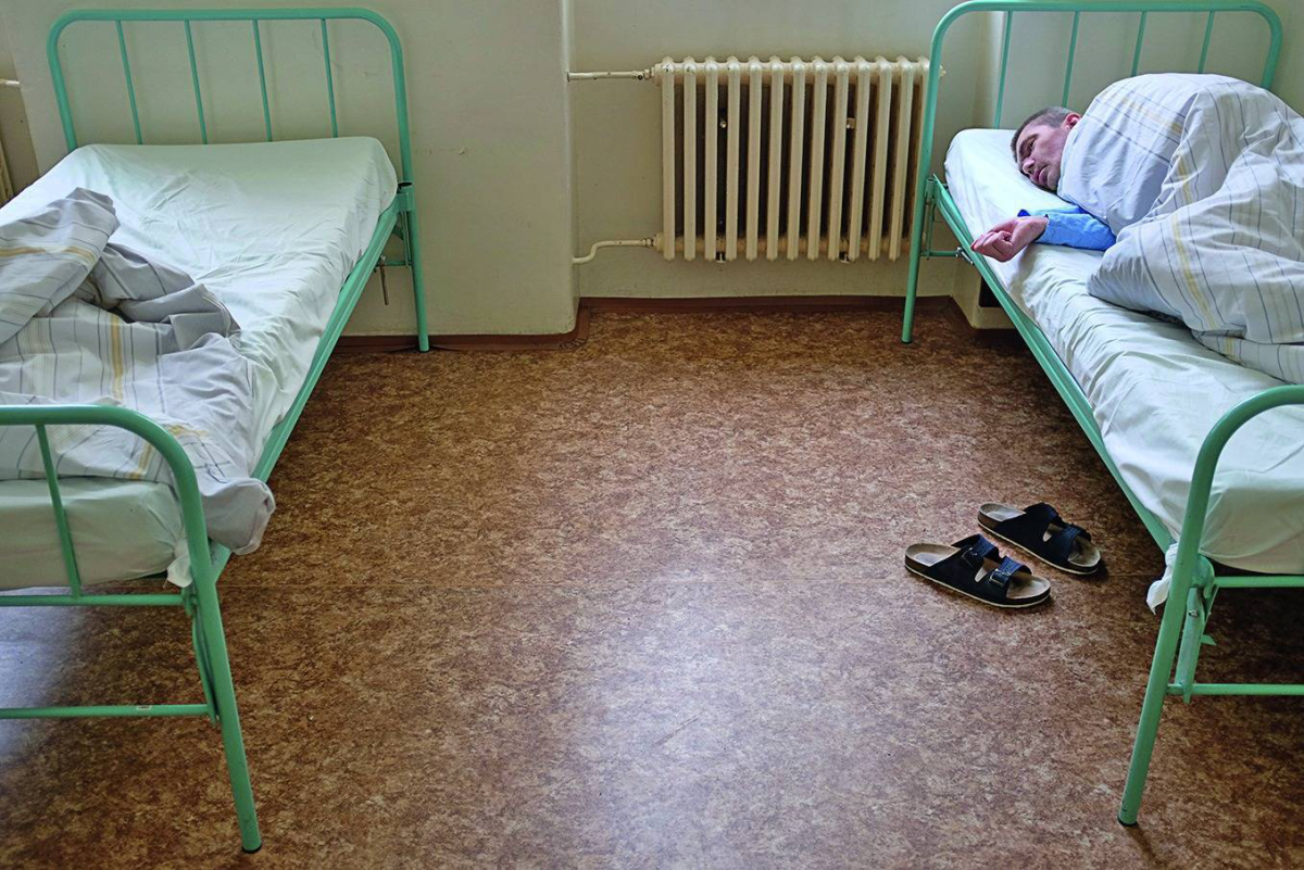 Paciente descansando en una cama de una sala de hospital psiquiátrico