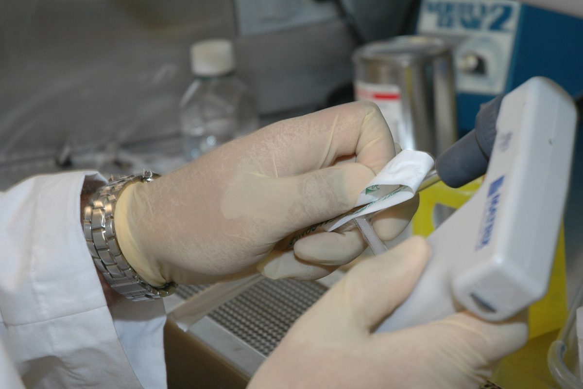 Manos enguantadas manejando una micropipeta y un tubo de ensayo en un laboratorio moderno