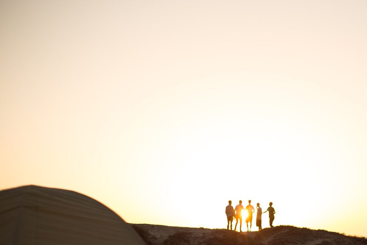 Siluetas de un grupo de jóvenes recortadas contra un atardecer luminoso