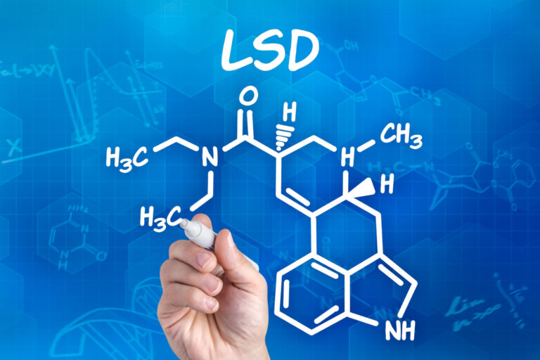 Hand with pen drawing the chemical formula of lsd