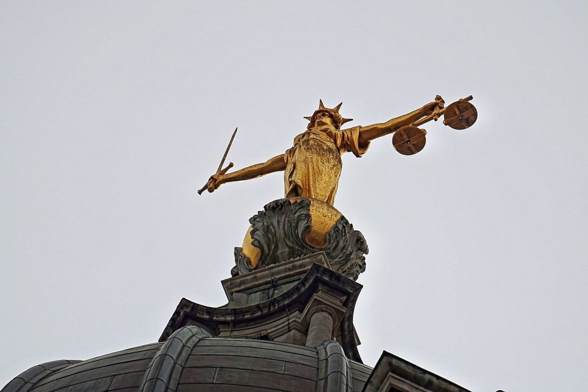Estatua dorada de la Justicia con la balanza y la espada en alto contra el cielo
