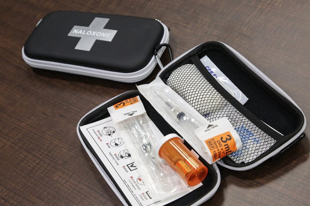 Estuche de naloxona abierto con jeringuillas, viales y hoja de instrucciones para revertir una sobredosis de opioides