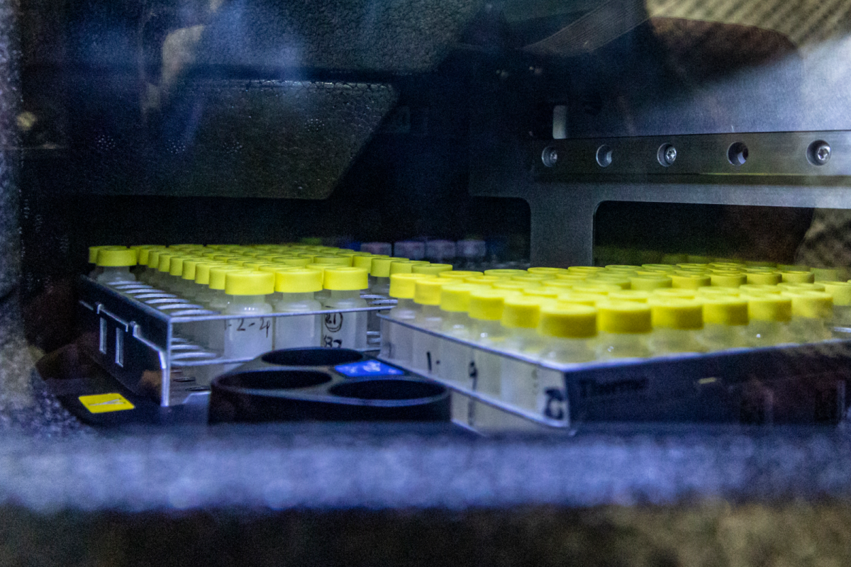 Bandeja con decenas de viales de muestra de tapón amarillo dispuestos en el compartimento de un espectrómetro de masas de laboratorio