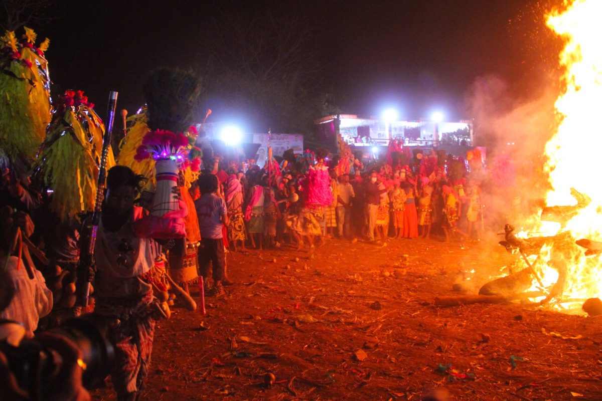 Grupo de personas reunidas de noche alrededor de una gran hoguera durante una celebración ritual comunitaria