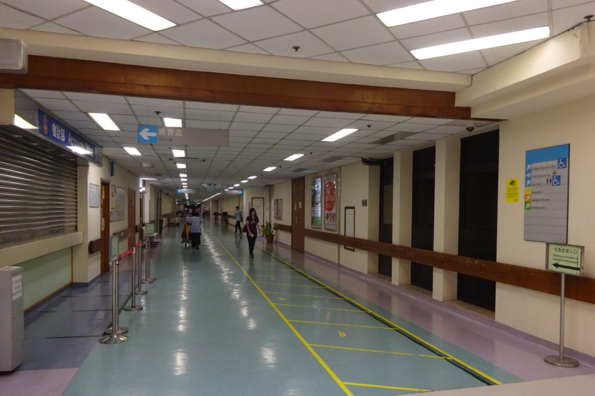 Pasillo amplio y luminoso de un hospital con señalización direccional y personal caminando al fondo