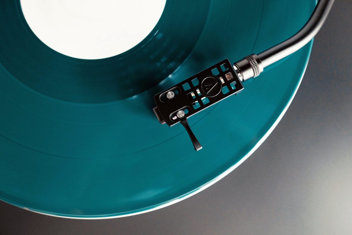 Primer plano del brazo y la aguja de un tocadiscos reproduciendo un disco de vinilo de color turquesa
