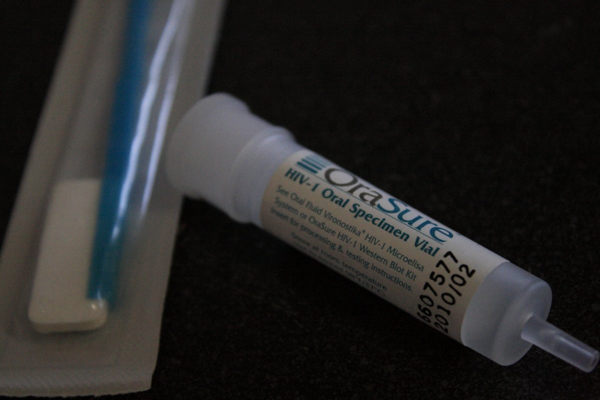 Vial de recogida de muestra oral de un kit de prueba rápida de VIH, sobre una superficie oscura.