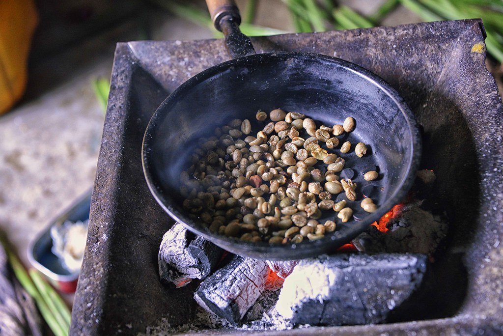 Granos de café verdes tostándose en una sartén de hierro sobre brasas de carbón, según el método tradicional etíope