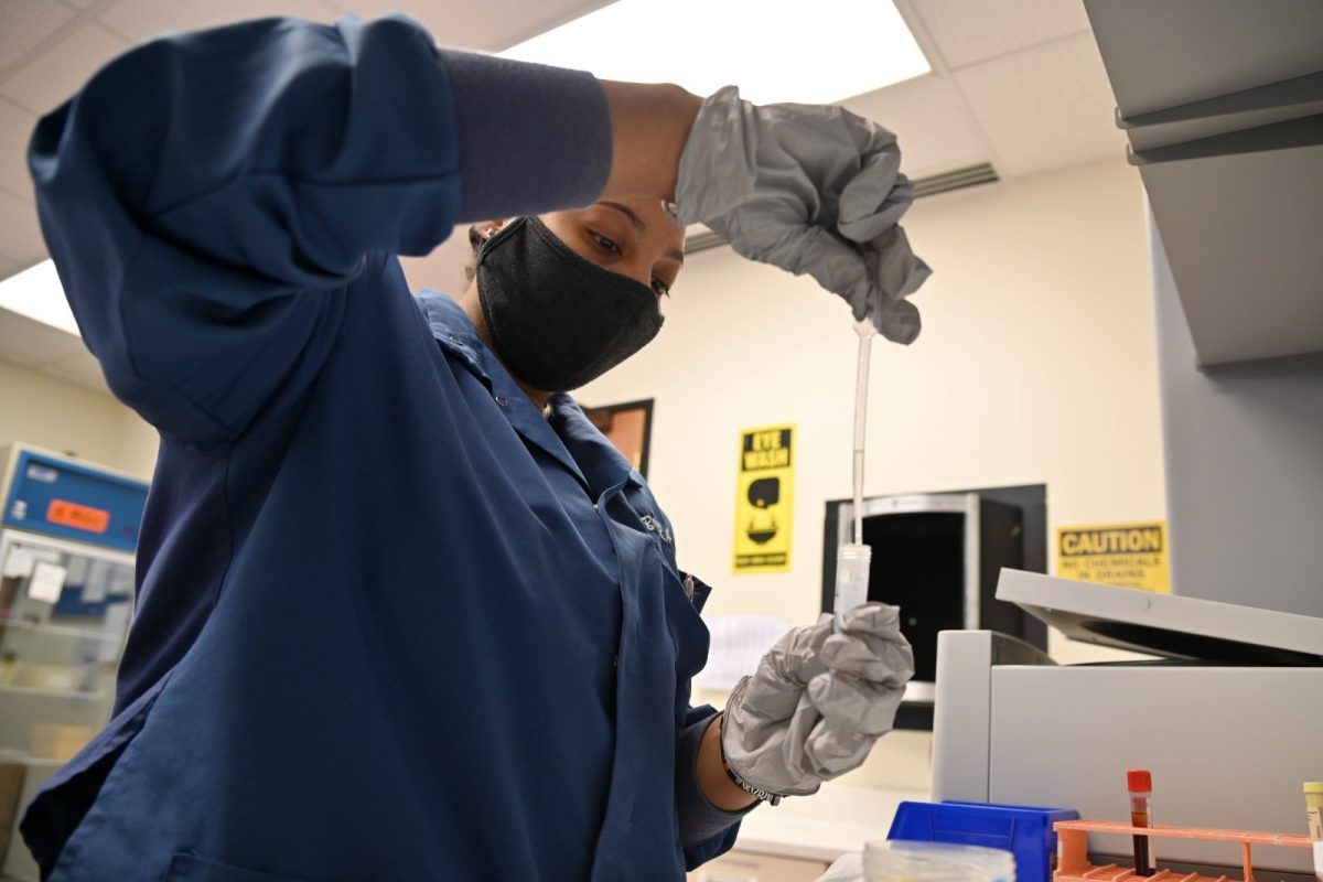 Personal sanitario con guantes y mascarilla preparando una muestra de orina para analizarla en un laboratorio clínico