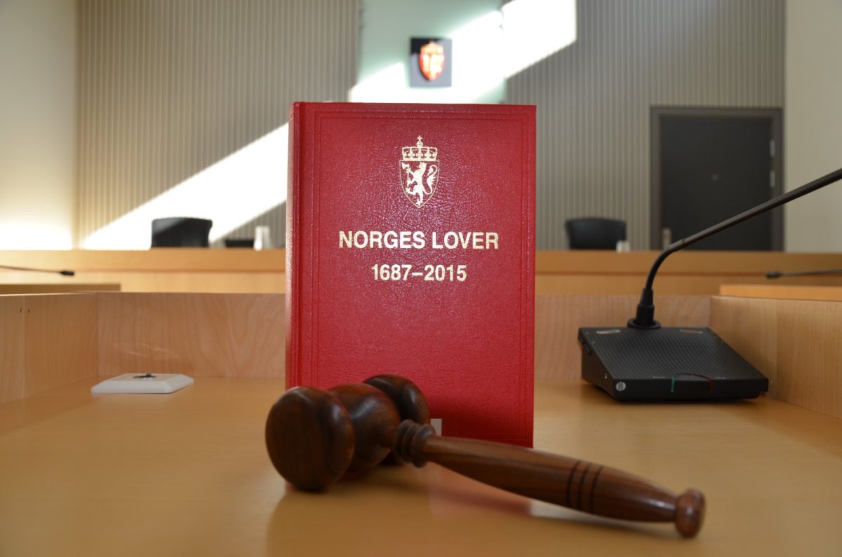 Libro de leyes de tapa roja junto a un mazo de juez de madera sobre la mesa de una sala de tribunal