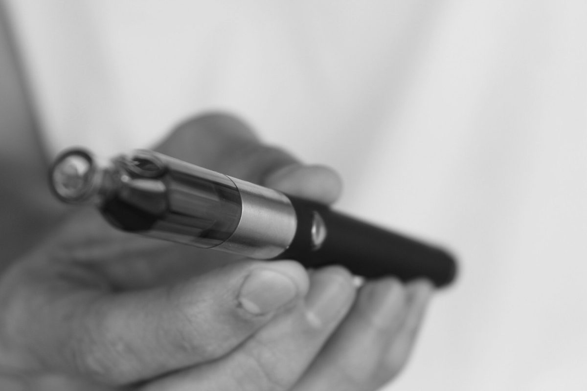 Fotografía en blanco y negro de una mano sosteniendo un cigarrillo electrónico o vaporizador en primer plano