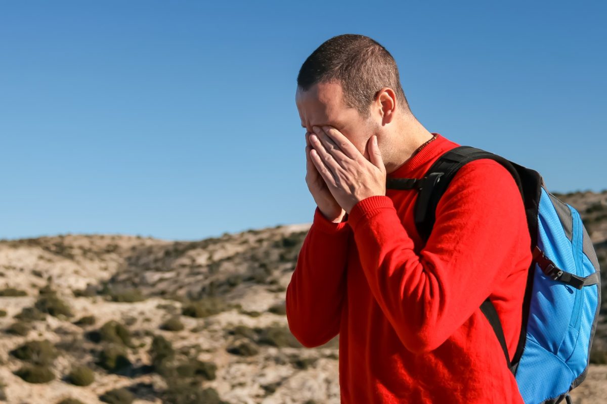 Hombre al aire libre presionándose el rostro con ambas manos por un fuerte dolor de cabeza
