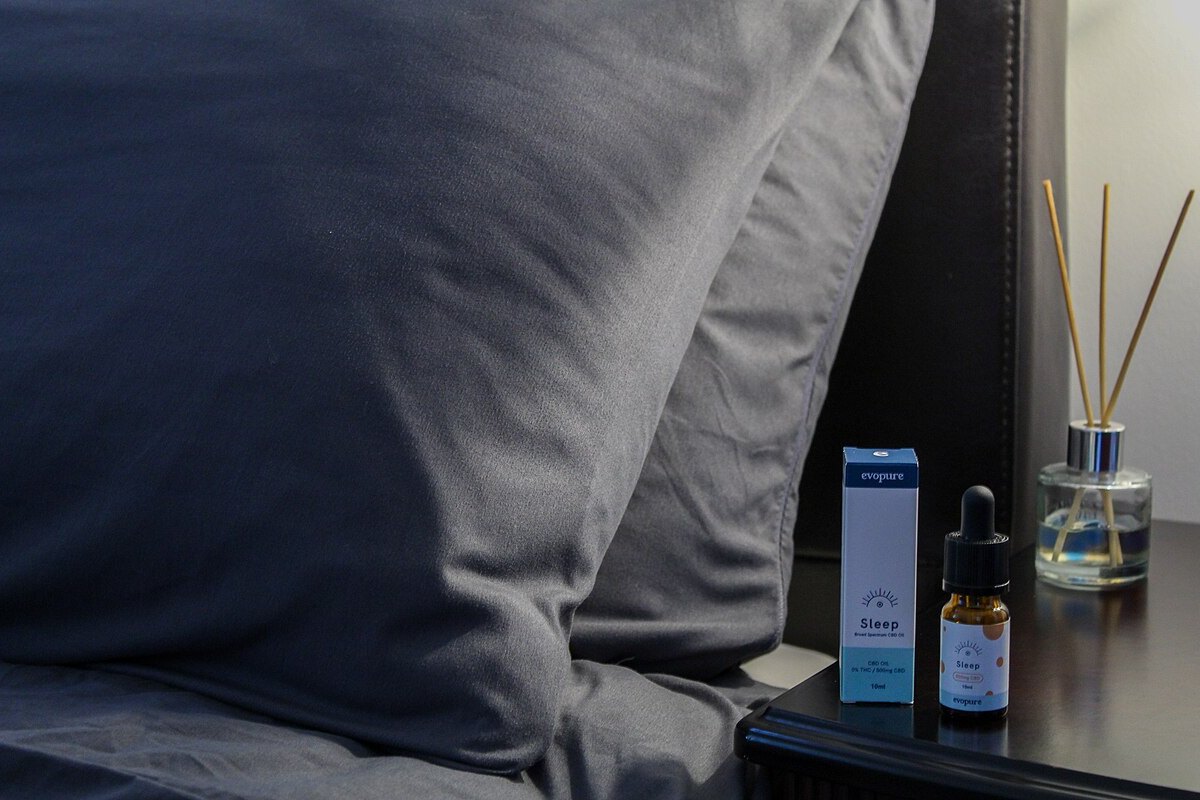 Frasco y caja de aceite de CBD sobre una mesilla de noche junto a un difusor de aromas