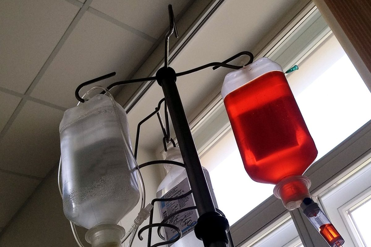 Bolsas de suero e infusión intravenosa colgadas de un soporte hospitalario, una de ellas con líquido rojo