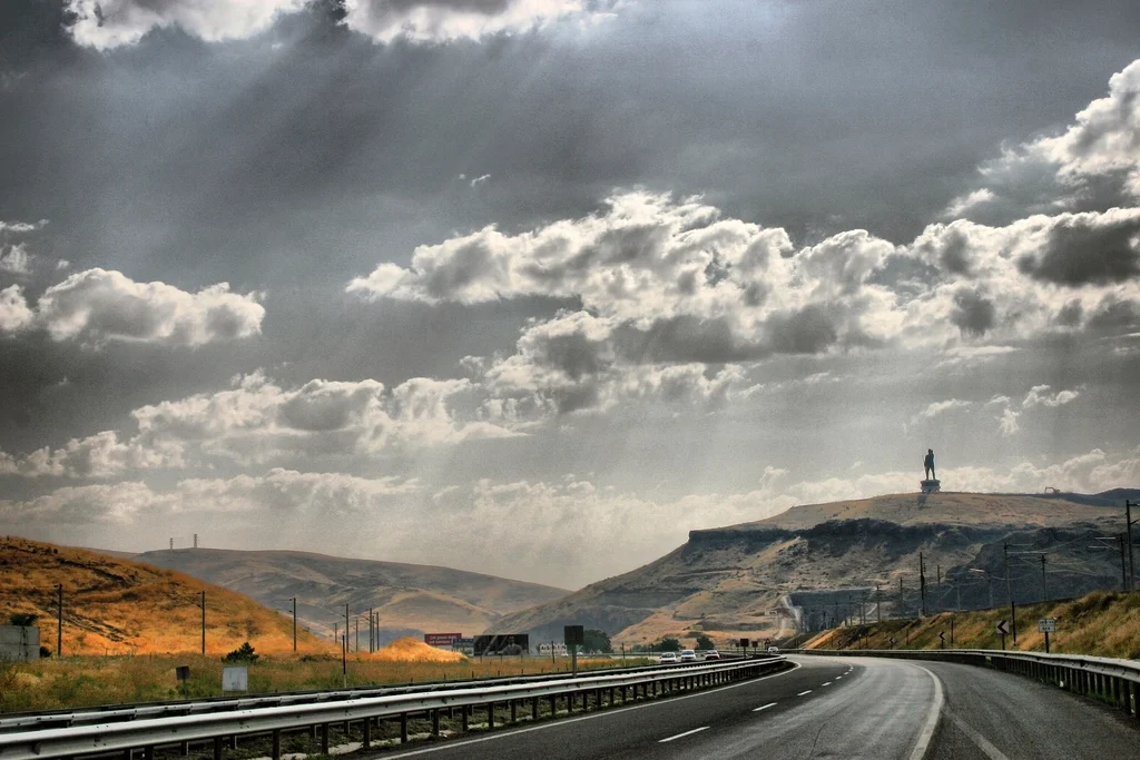 Carretera vacía que se extiende hacia el horizonte bajo un cielo nublado, sin vehículos en primer plano