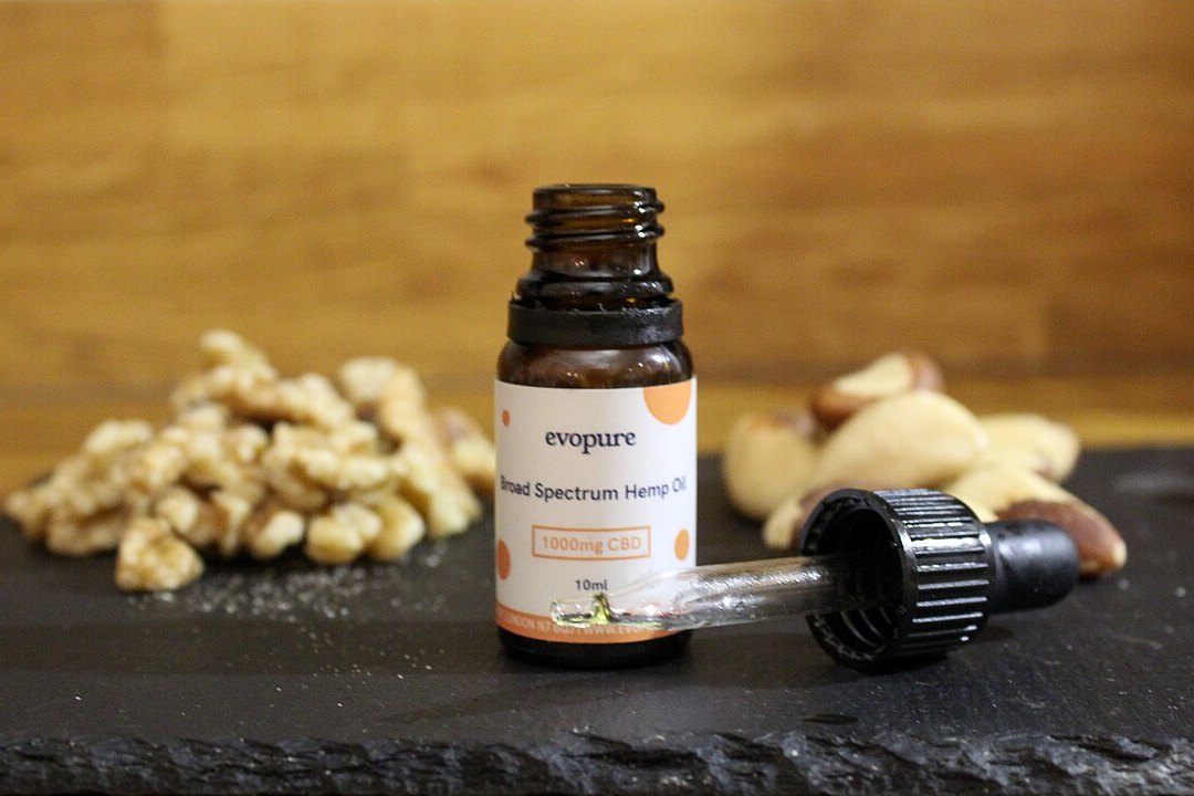 Frasco de aceite de CBD con gotero apoyado junto a nueces y frutos secos