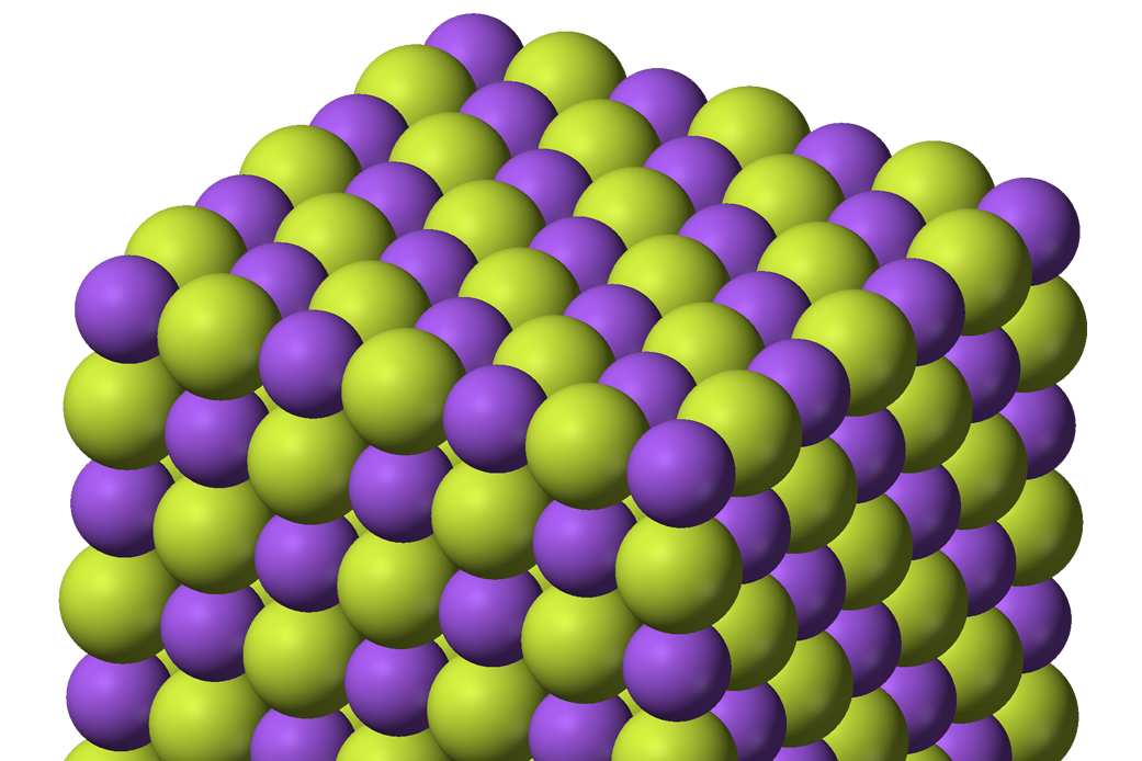 Modelo tridimensional de la red cristalina iónica del fluoruro de sodio, con esferas verdes y moradas alternadas