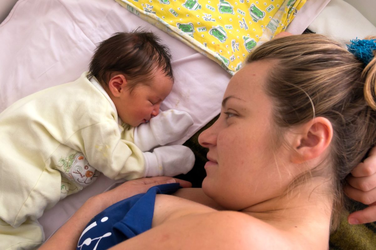 Una madre mira a su bebé recién nacido acostado junto a ella