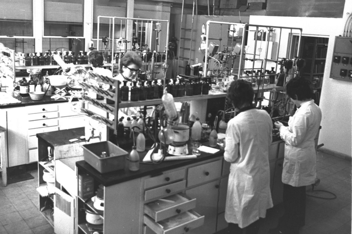 Personal con bata blanca trabajando entre material de vidrio en un laboratorio de investigación farmacéutica