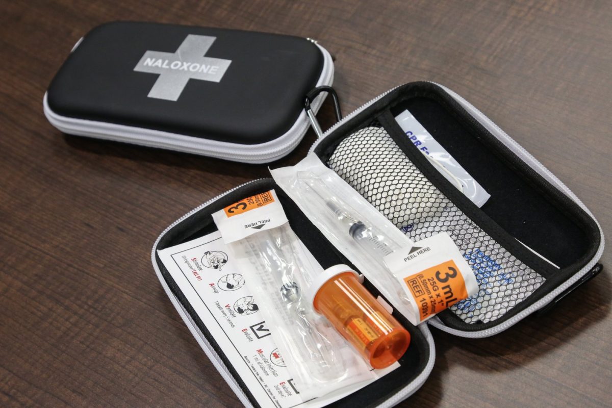 Kit de naloxona abierto con jeringa, vial e instrucciones sobre una mesa de madera