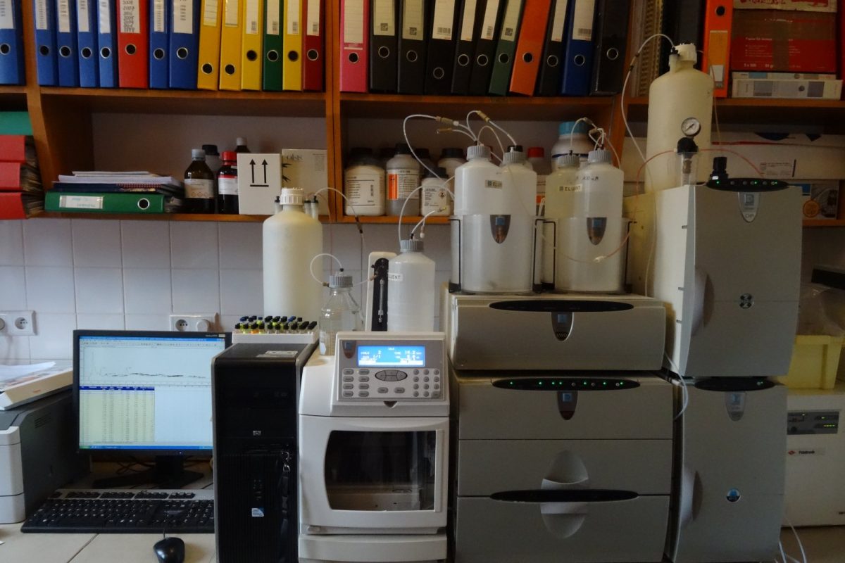 Equipo de cromatografía en un laboratorio, con monitor mostrando un cromatograma y viales de muestra