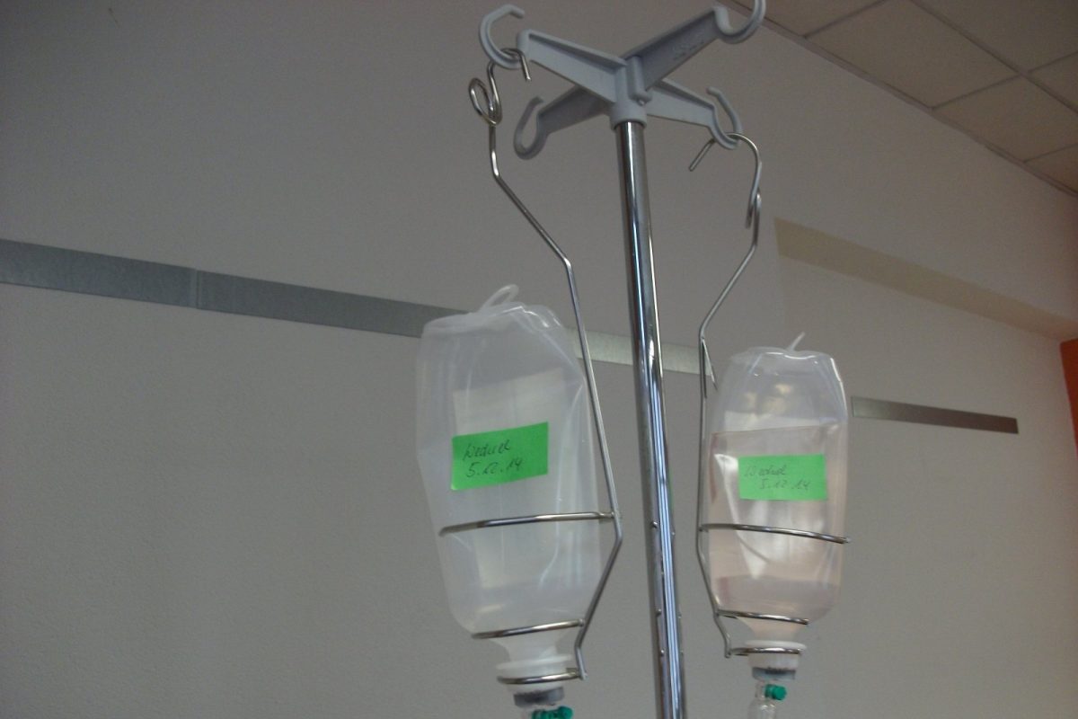 Dos frascos de suero para infusión intravenosa colgados de un pie de gotero metálico en una sala hospitalaria