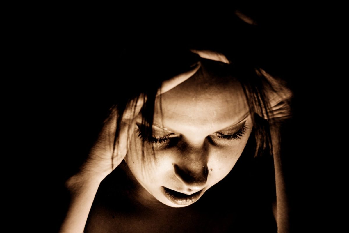 Persona con la cabeza entre las manos y los ojos cerrados durante un episodio de dolor de cabeza