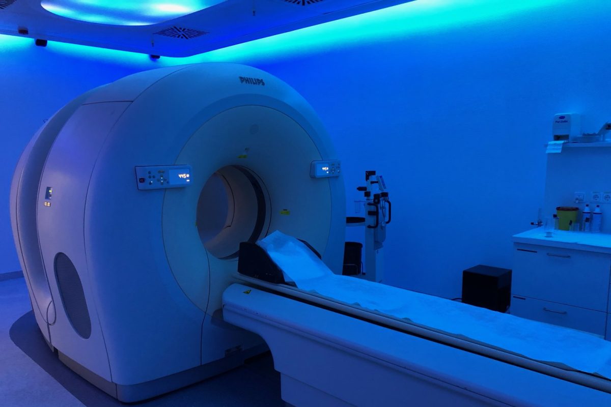 Escáner PET-CT en una sala clínica iluminada en azul, con la camilla extendida hacia el túnel del aparato
