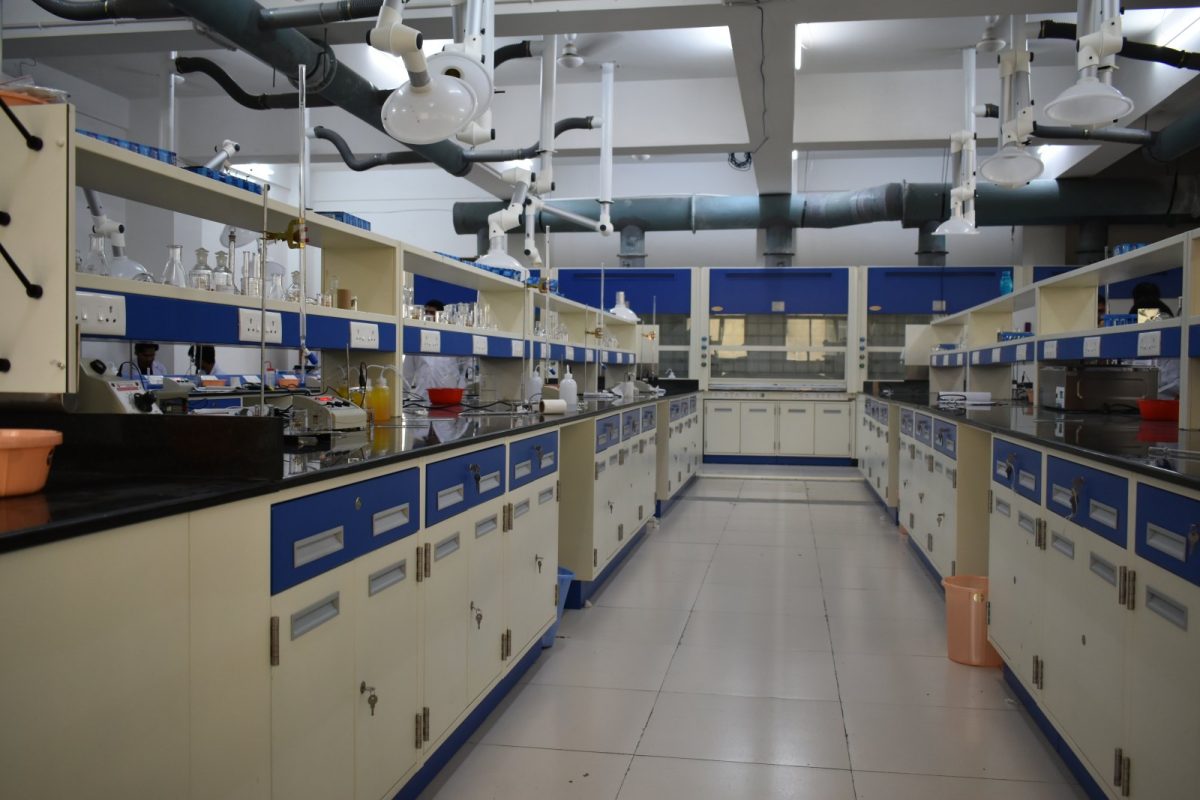 Laboratorio de química con mesas de trabajo, material de vidrio, campanas extractoras y brazos de extracción de gases