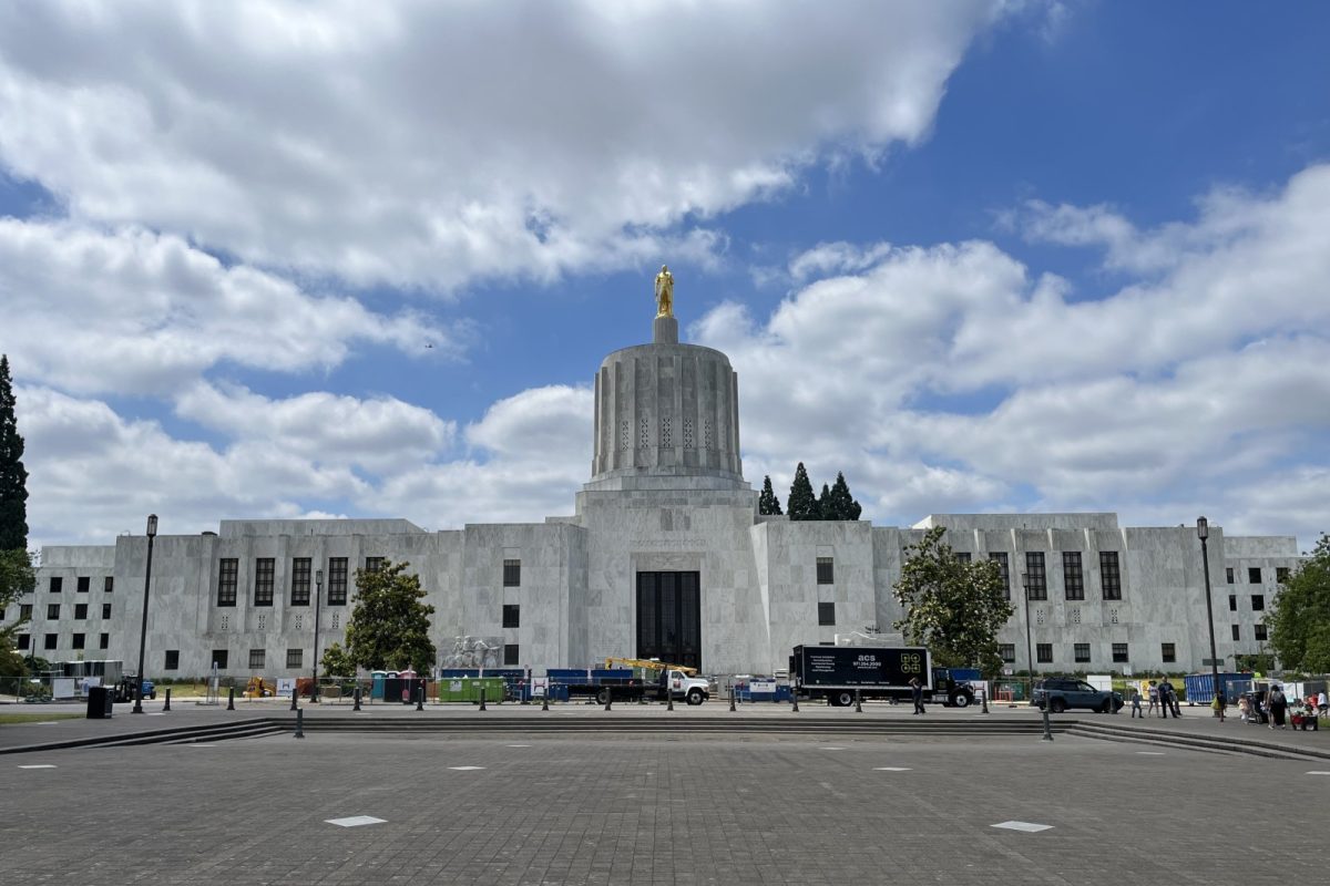 Fachada de mármol blanco del Capitolio de Oregón, con su torre cilíndrica rematada por una figura dorada, bajo un cielo con nubes
